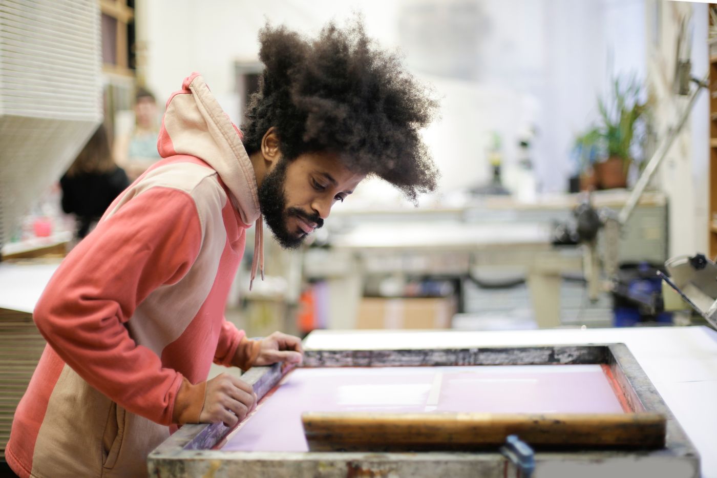 An artisan leaning over a press in a studio
