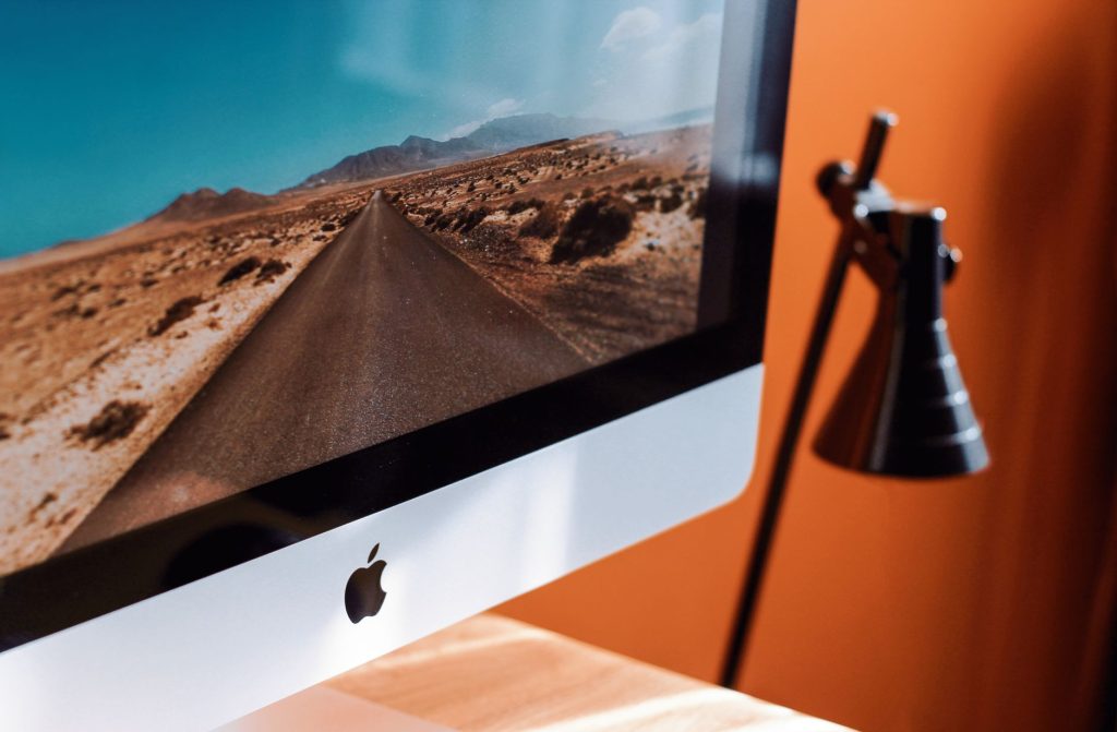 A modern desk with an iMac and a desk lamp