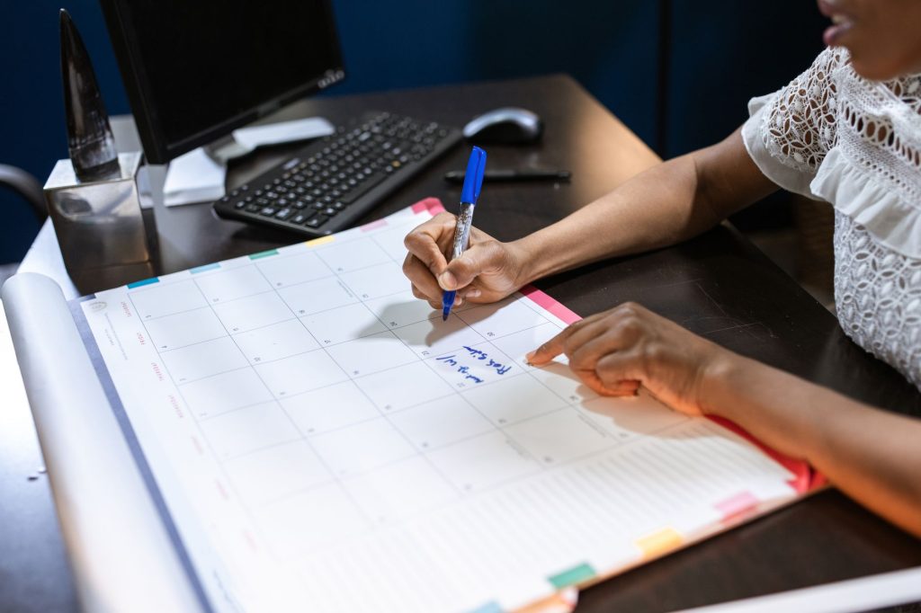 A hand writing on a large desk calendar