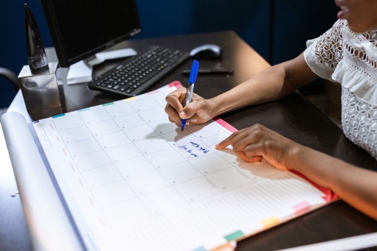 A hand writing on a large desk calendar