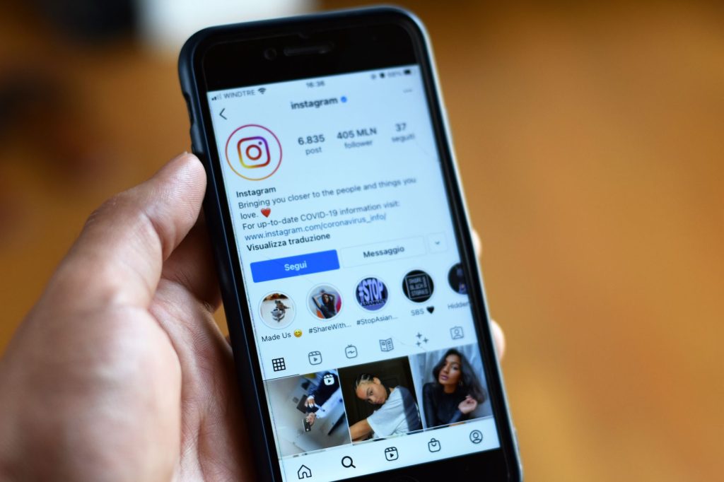 A hand holding a phone showing a social media profile