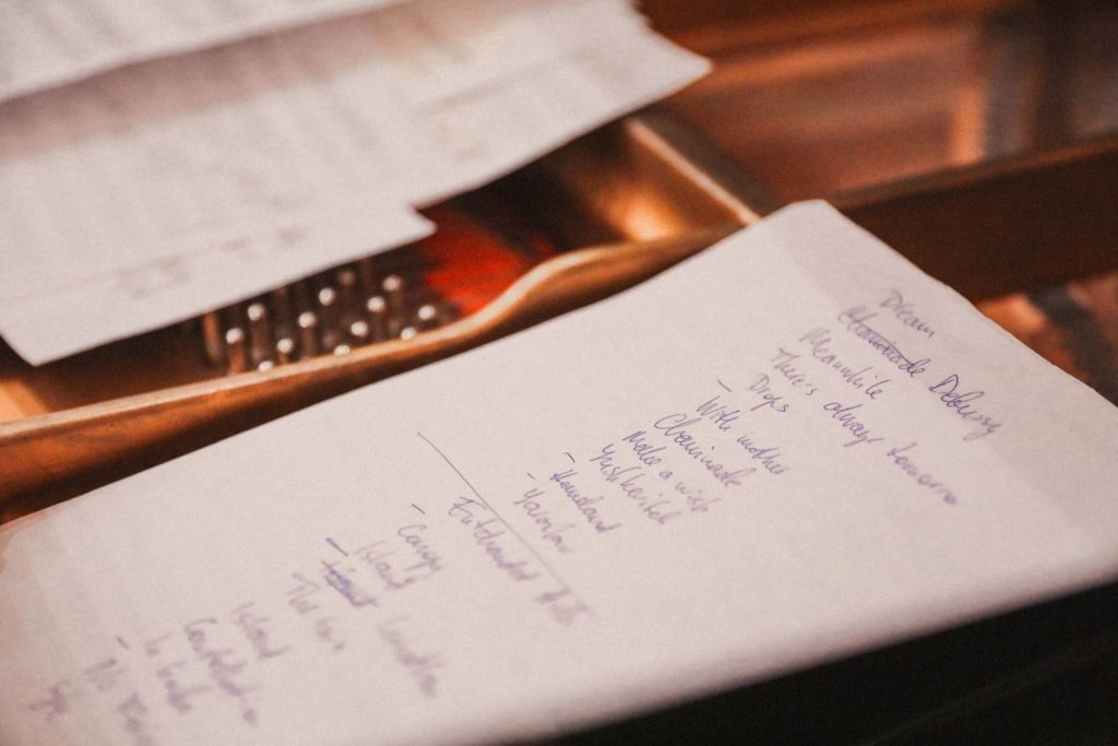 Handwritten checklist in blue ink on cream paper lit by warm desk light